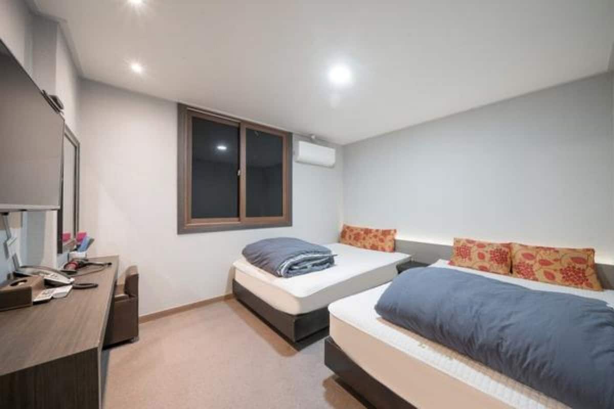 Un dormitorio con dos camas, un escritorio y una ventana.