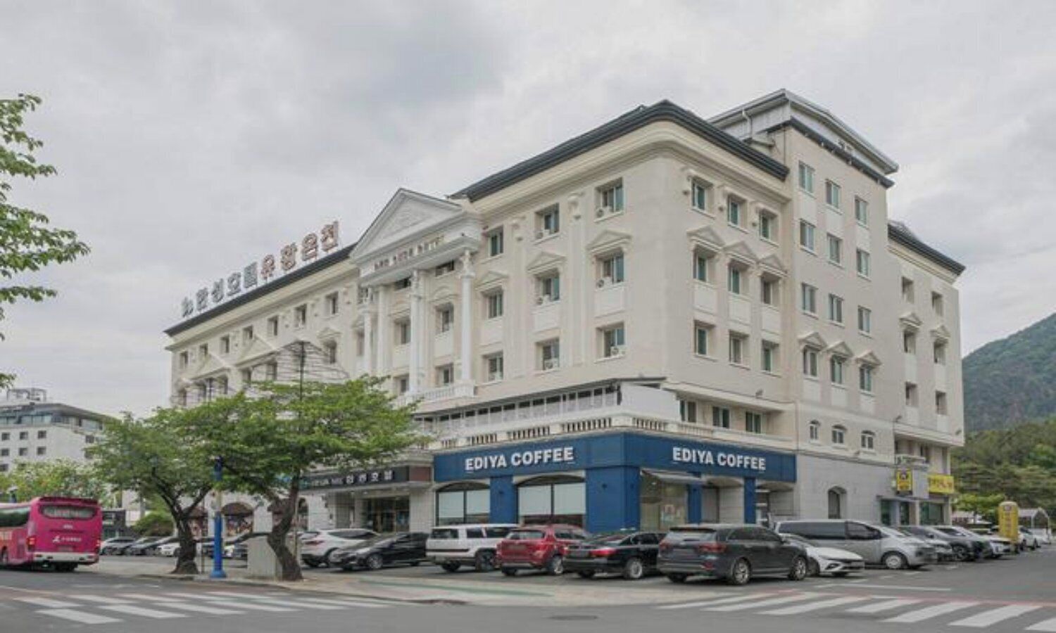 A multi-story hotel with a classic architectural style, featuring a prominent entrance with signage for 'EDIYA COFFEE' on the ground floor.