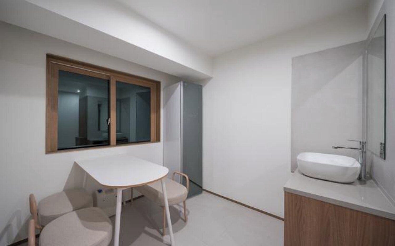 A modern bathroom with a large window, a white sink, and a small table with chairs.