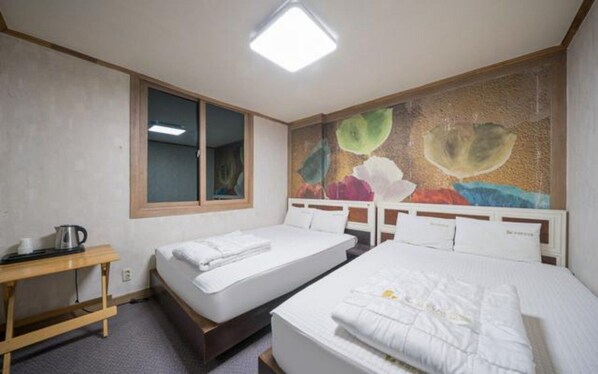 A hotel room with two beds, a wooden nightstand, a window, and a painting on the wall.