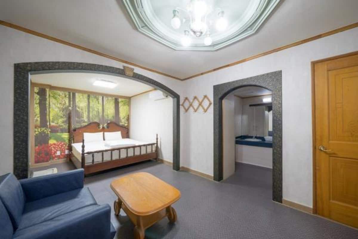 Una habitación con cama, sofá, una mesita y una puerta de madera.