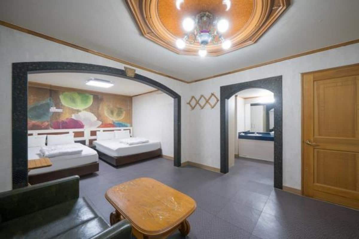 Una habitación de hotel con cama, una mesita, un espejo y una puerta.
