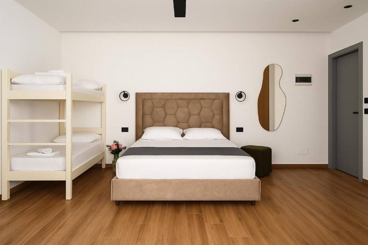 A bedroom with a bed, a bedside table, a lamp, a wardrobe, and a mirror.
