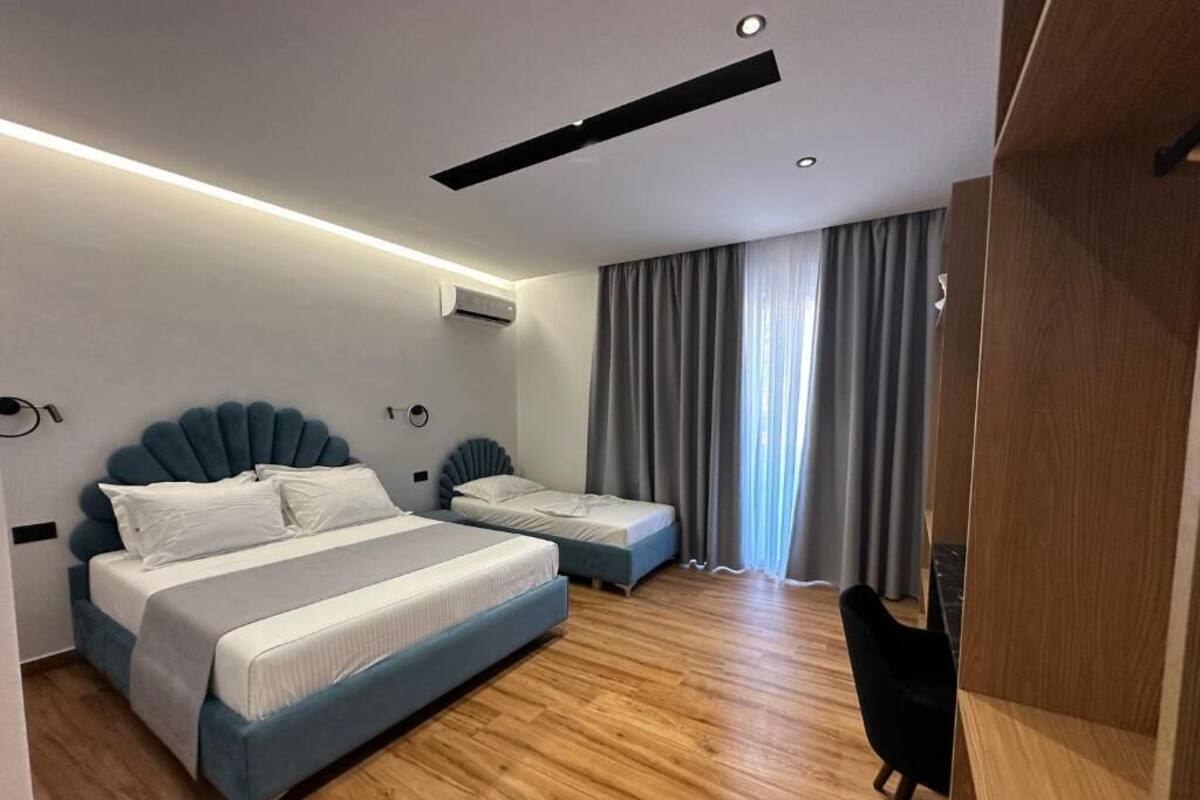 A modern hotel room with a large bed, a smaller bed, a desk, and a chair.
