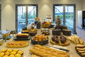 En morgenmadsbuffet med et udvalg af kager, brød og frugt.