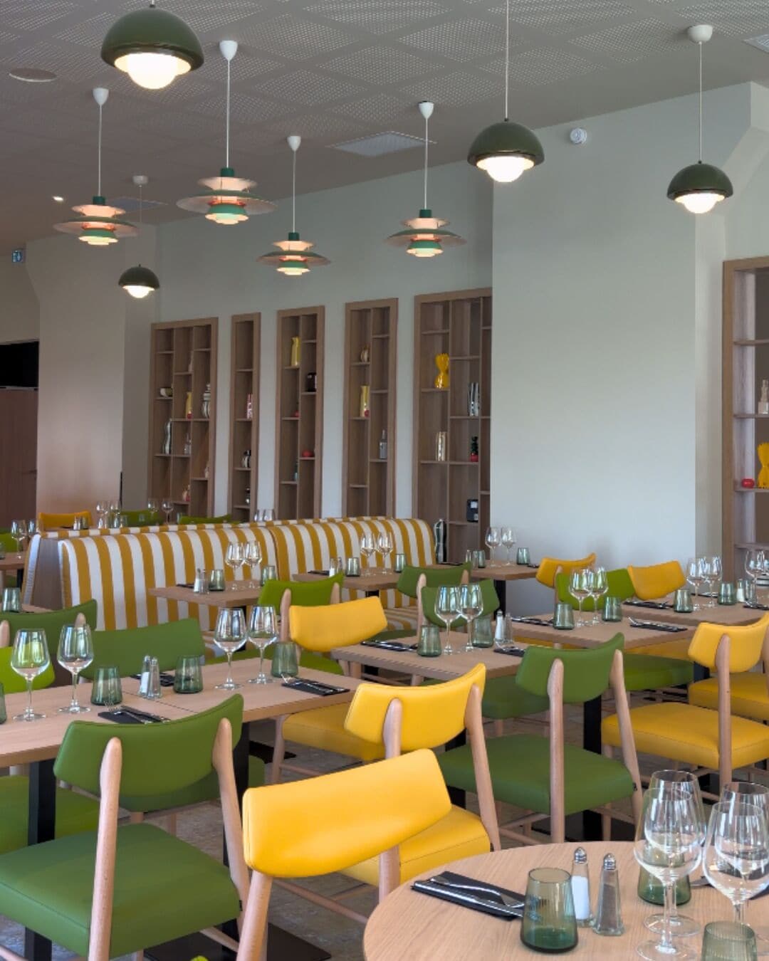 Een restaurantinterieur met meerdere eettafels, stoelen en hangende lampen.