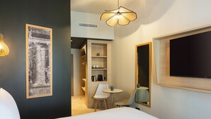 A hotel room with a bed, a desk with chairs, a television, a framed picture on the wall, and a ceiling light fixture. - Mercure Nîmes Centre Arènes (Nimes)