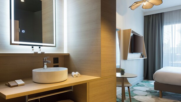 A modern bathroom with a large mirror, sink, and towel storage. - Mercure Nîmes Centre Arènes (Nimes)