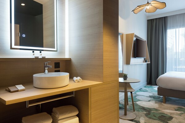 A modern bathroom with a large mirror, sink, and towel storage. - Mercure Nîmes Centre Arènes (Nimes)