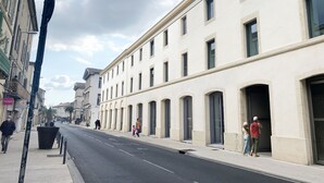A street with buildings, a sidewalk, and a few pedestrians. - Mercure Nîmes Centre Arènes (Nimes)