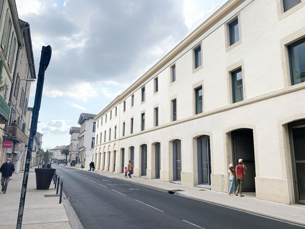 A street with buildings, a sidewalk, and a few pedestrians. - Mercure Nîmes Centre Arènes (Nimes)