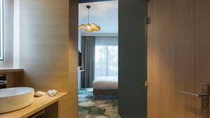 A modern hotel room with a large round sink, a bed, a ceiling light, and a floral carpet. - Mercure Nîmes Centre Arènes (Nimes)