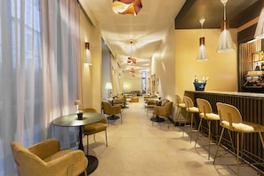 A hotel lobby with round tables and chairs, a bar area, and a ceiling with decorative lighting. - Mercure Nîmes Centre Arènes (Nimes)