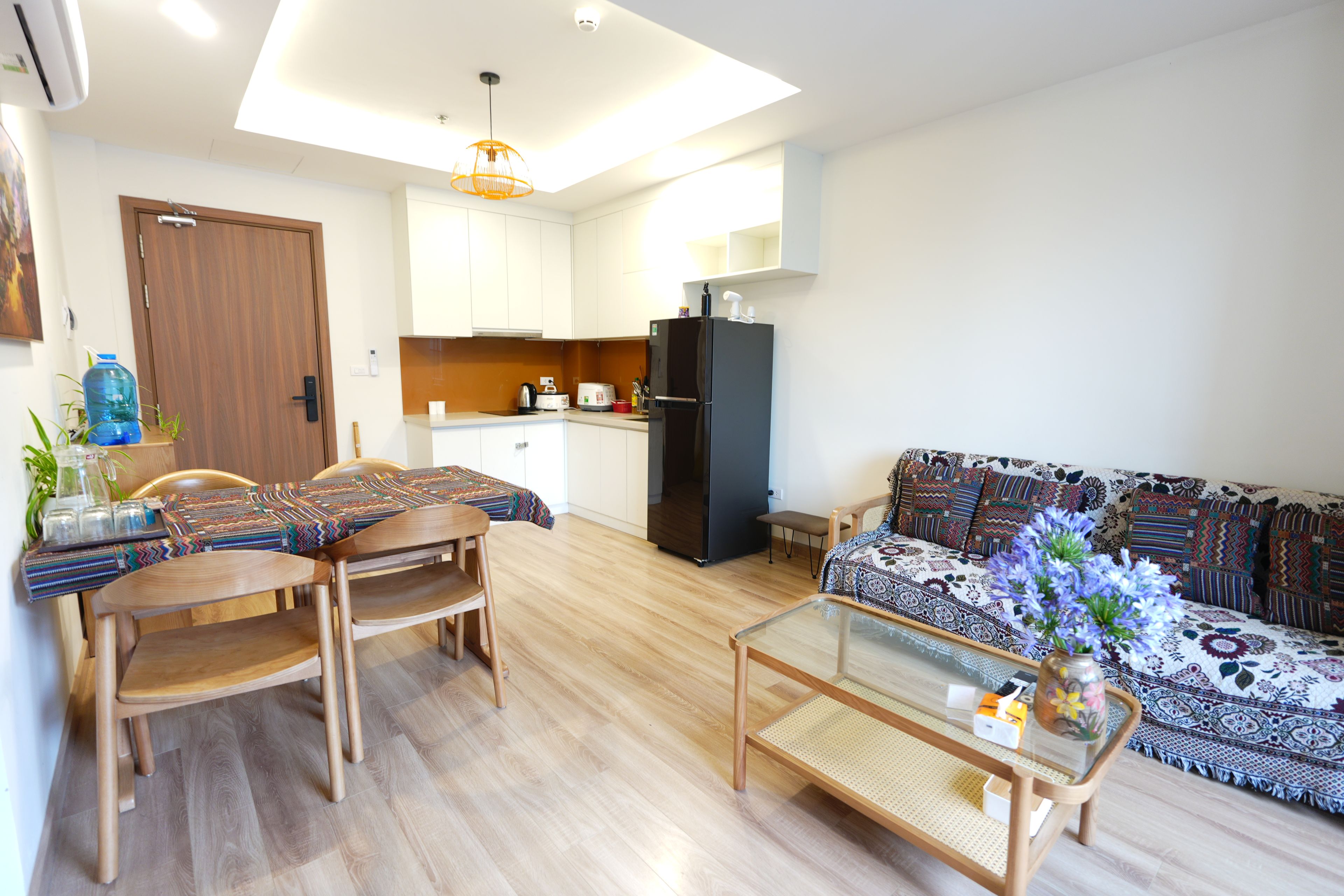 A modern living room with a sofa, a coffee table, and a dining area with chairs and a table.