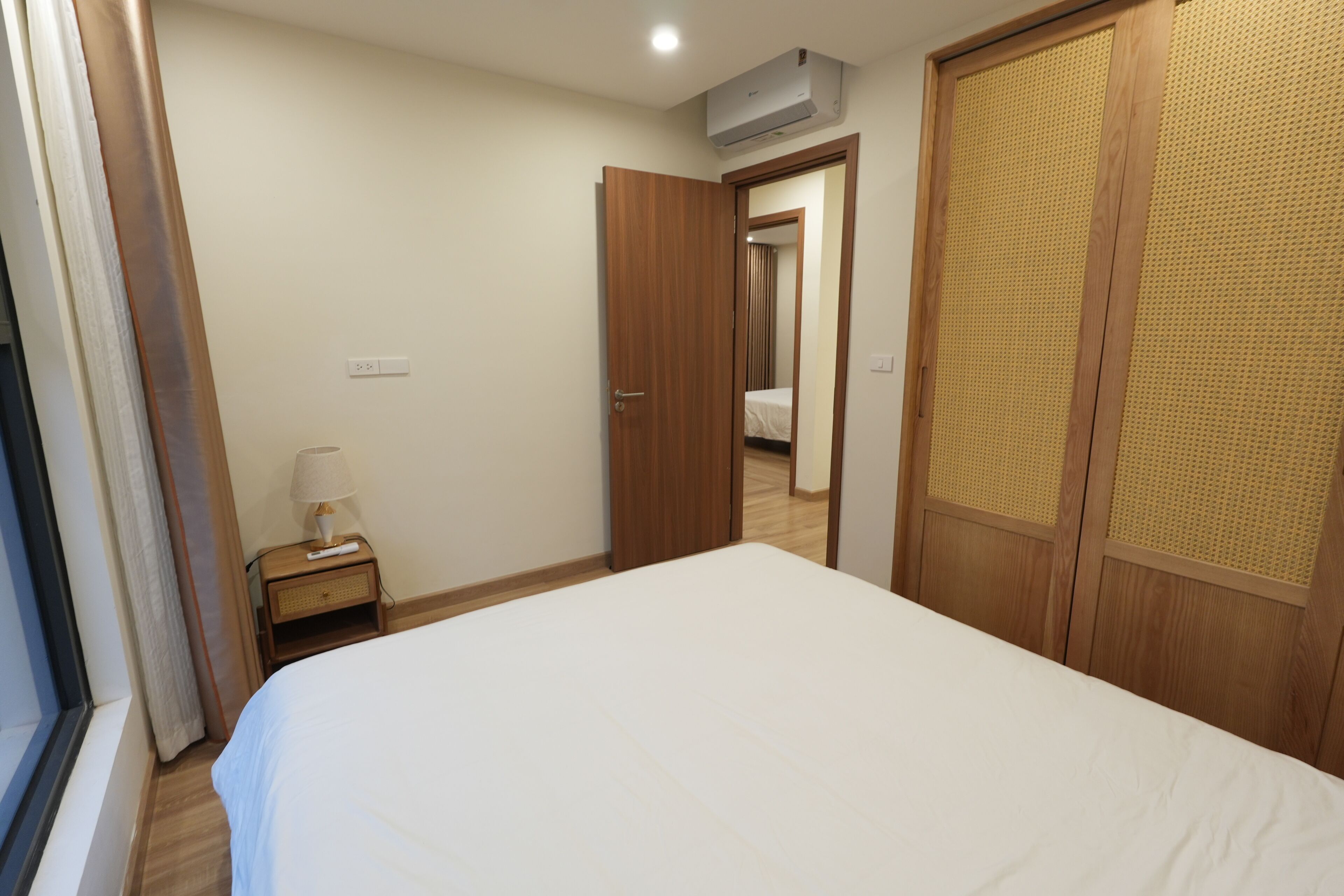 Una camera da letto con un letto, un comodino, una lampada, un armadio e un condizionatore d'aria.