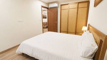 A bedroom with a bed, a wooden headboard, a bedside lamp, and a wardrobe with a woven door.