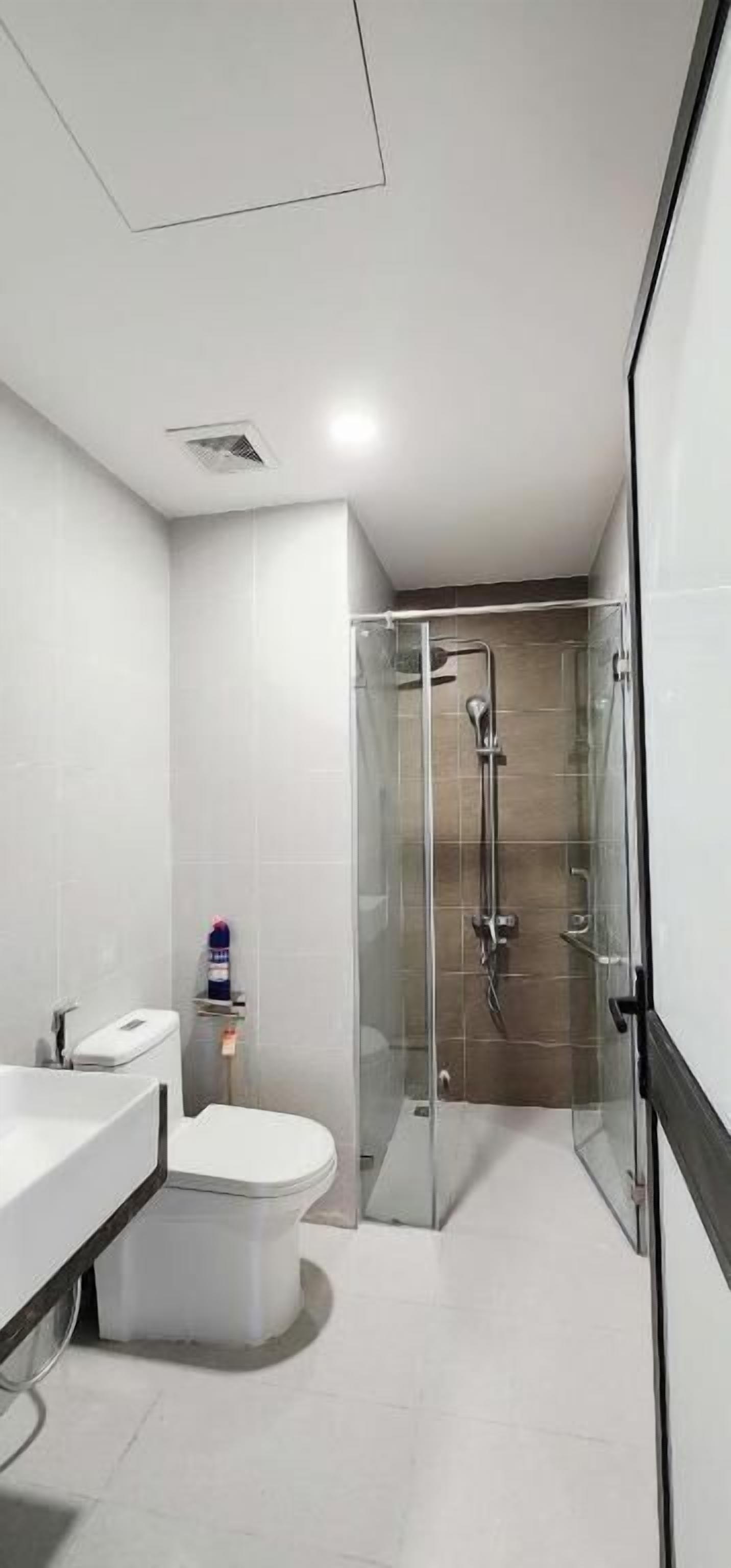 Un baño moderno con ducha envuelta en vidrio, un lavabo blanco y un inodoro.