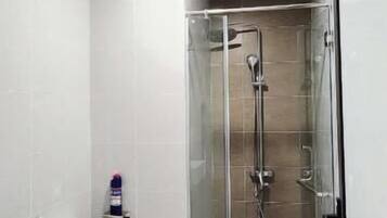 Un baño moderno con ducha envuelta en vidrio, un lavabo blanco y un inodoro.