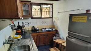 A small kitchen with a sink, stove, and a refrigerator. - The Sheltor (Chennai)