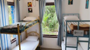 A room with bunk beds, a window with curtains, and a sign indicating air conditioning. - The Sheltor (Chennai)