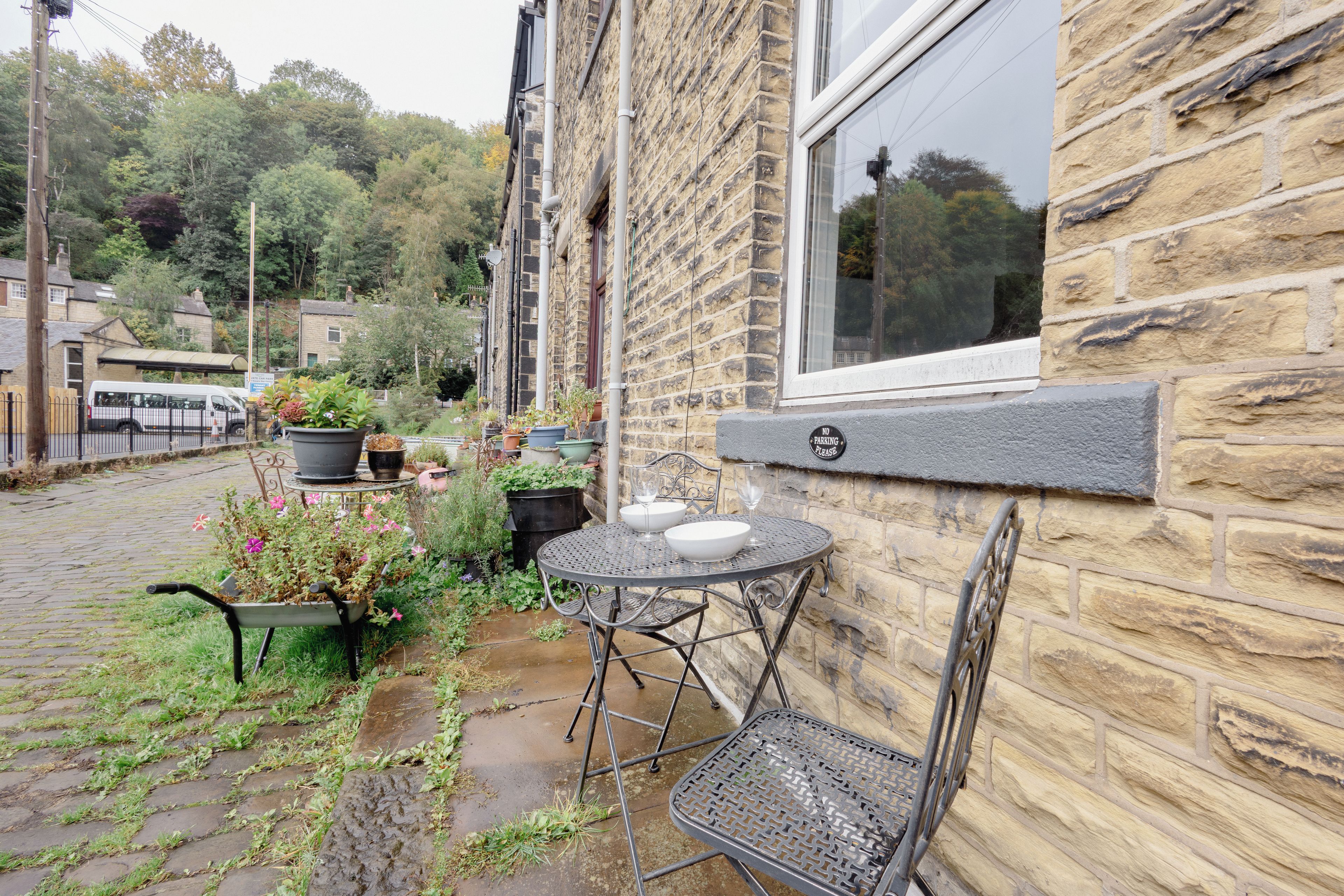 A stone building with a metal table and chairs outside, a window, and a 'NO PARKING' sign.