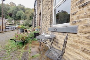 A stone building with a metal table and chairs outside, a window, and a 'NO PARKING' sign.