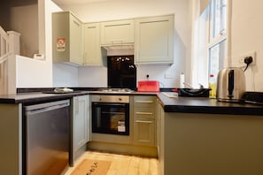 A kitchen with a dishwasher, oven, and a red appliance on the counter.