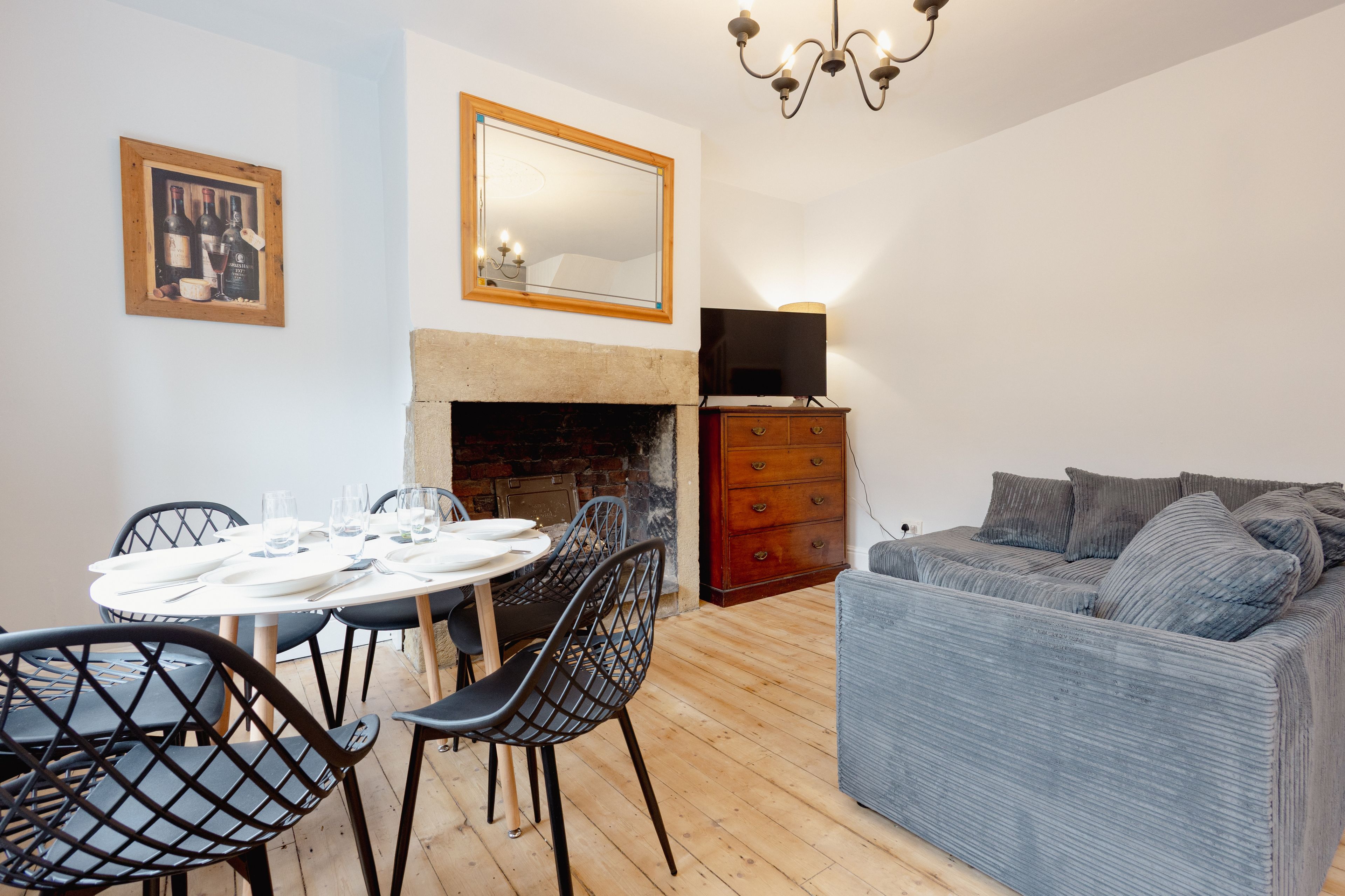 A dining area with a round table and chairs, a fireplace, a sofa, and a television.
