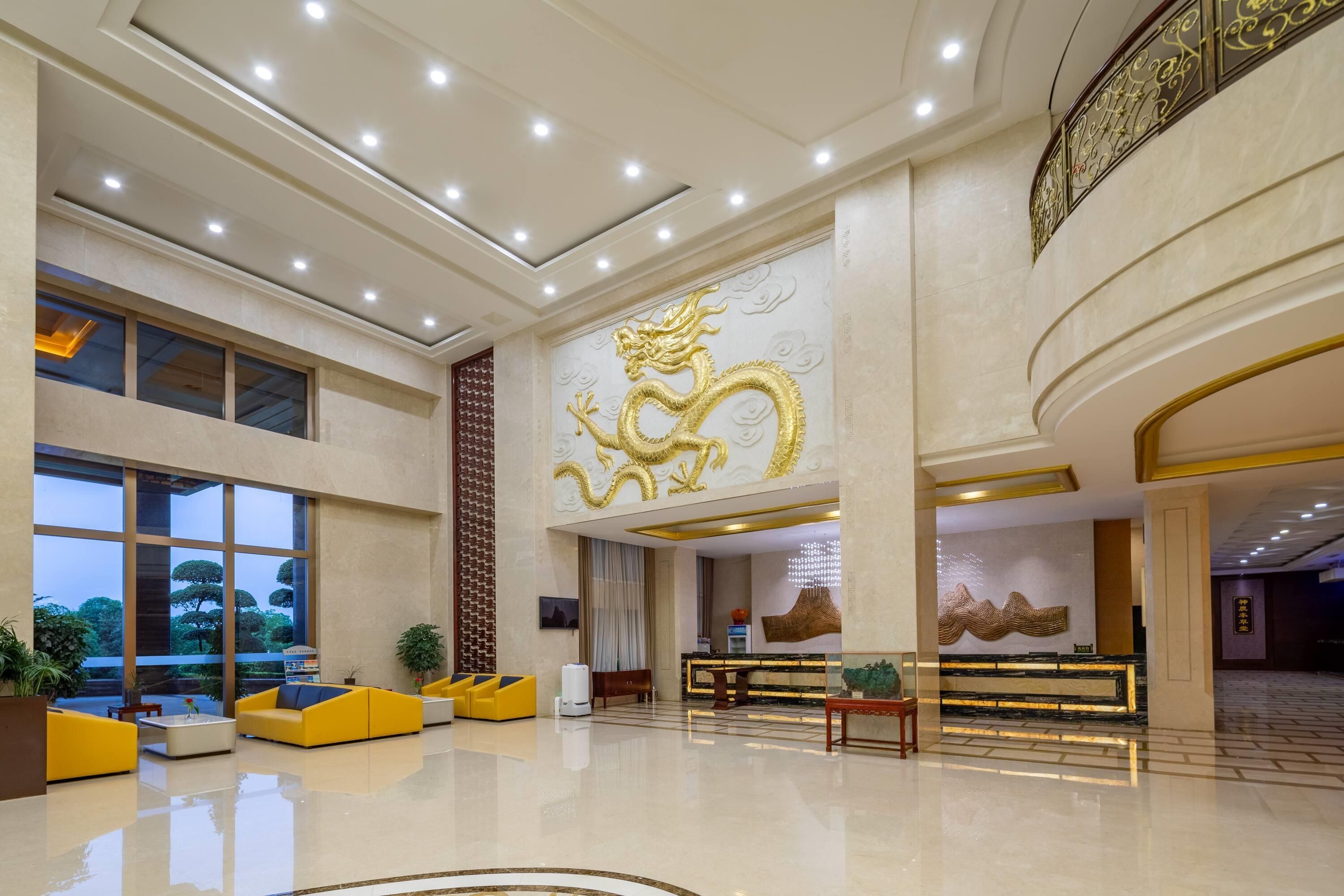 Un vestíbulo amplio con un gran mural de un dragón dorado, asientos modernos y una mesa de recepción.