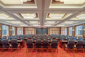 A large conference room with rows of tables and chairs, a stage at the front, and a patterned carpet. - Days Hotel by Wyndham Suixian Shennong (Suizhou)