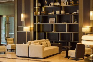 Un vestíbulo con un sofá, sillones, una estantería y una lámpara.