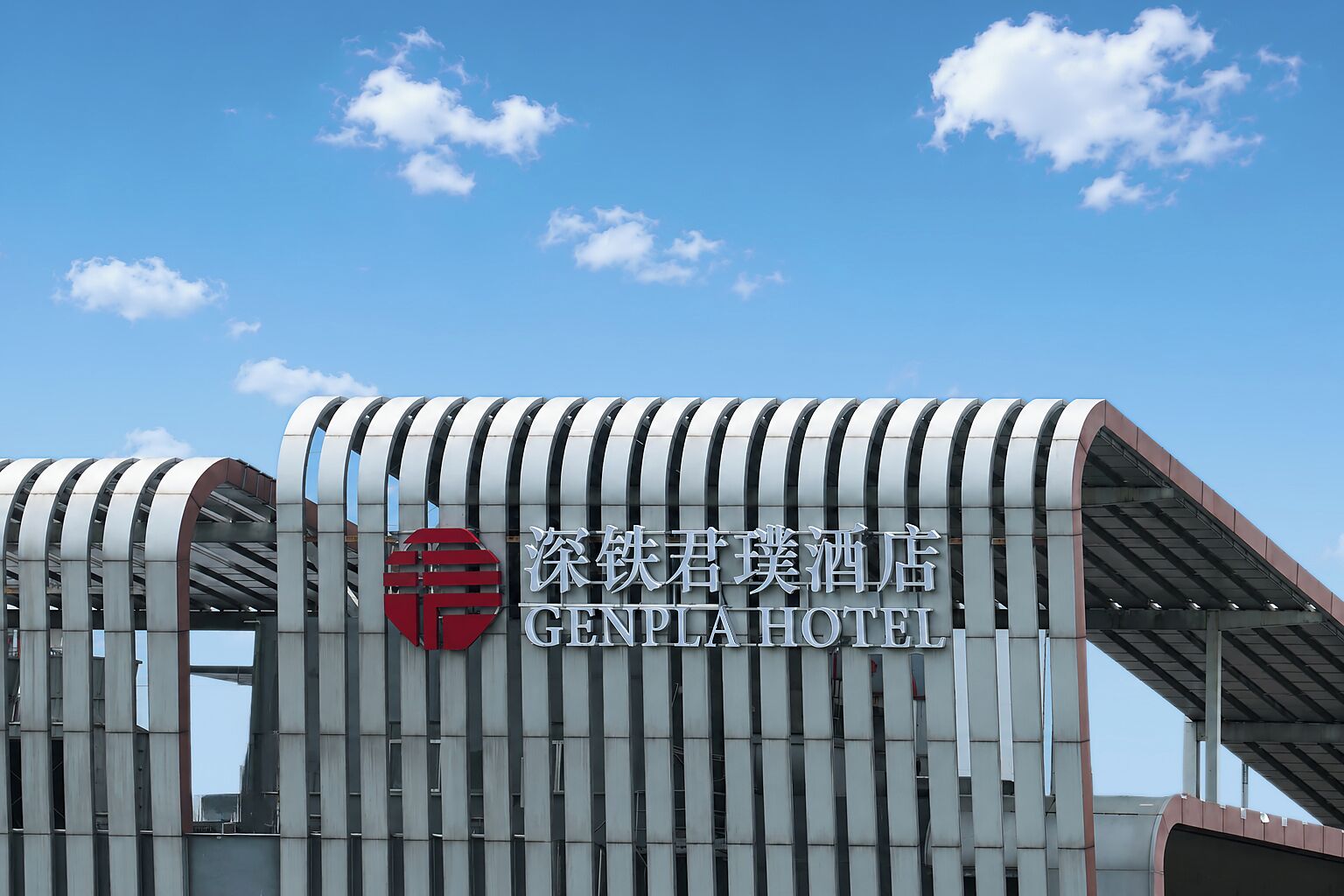 A modern hotel with a distinctive curved facade and a prominent logo.