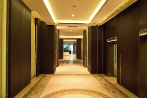 A long, narrow hallway with a patterned carpet, dark walls, and a ceiling with recessed lighting. - Genpla Hotel by Shenzhen Metro (Shenzhen)