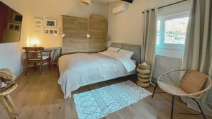 Un dormitorio con cama, escritorio, silla, lámpara colgante y ventana con cortinas.