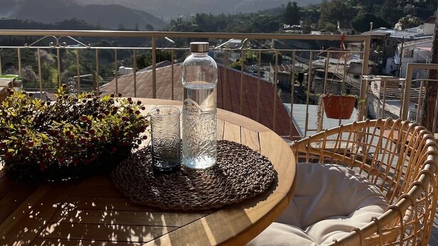 Un balcón con una mesa, sillas, una botella y una planta.
