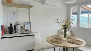 Cocina compacta con estufa integrada, encimera blanca, lámpara colgante y ventana con vistas.
