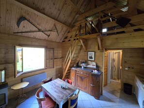 Ein Holzblock-Interieur mit Esstisch, Stühlen, einer Küchenzeile und einer Treppe.