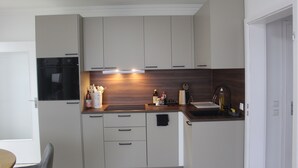 A compact kitchen with white cabinets, a black oven, and a wooden countertop.