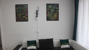 A room with a sofa, two pillows, and two wall-mounted paintings.