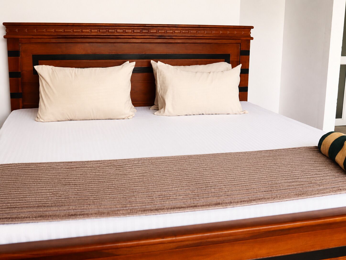 A bed with a wooden headboard, two pillows, and a brown bedspread.