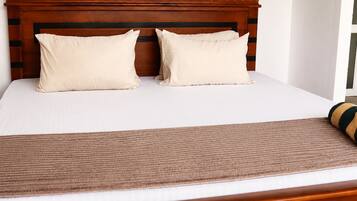 A bed with a wooden headboard, two pillows, and a brown bedspread.