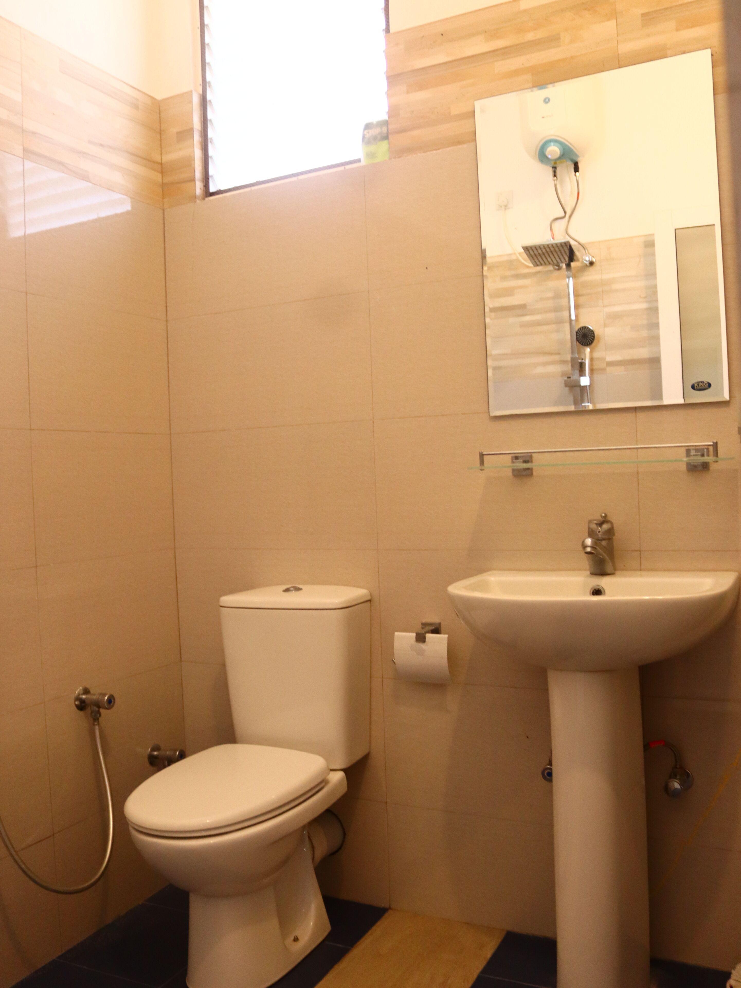 Et badeværelse med toilet, håndvask og bruser.