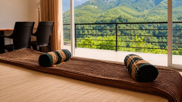 Habitació d'hotel amb un llit, dues cadires, una taula i vista a les muntanyes.