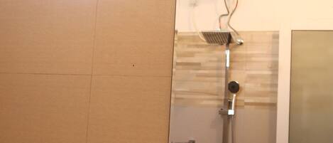A bathroom with a shower, a mirror, and a door.