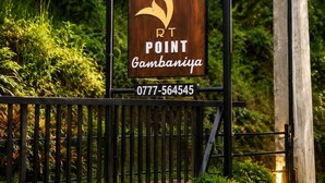 Un senyal de fusta amb un logo de cervís i el text 'RT POINT Gambaniya' i un número de telèfon.