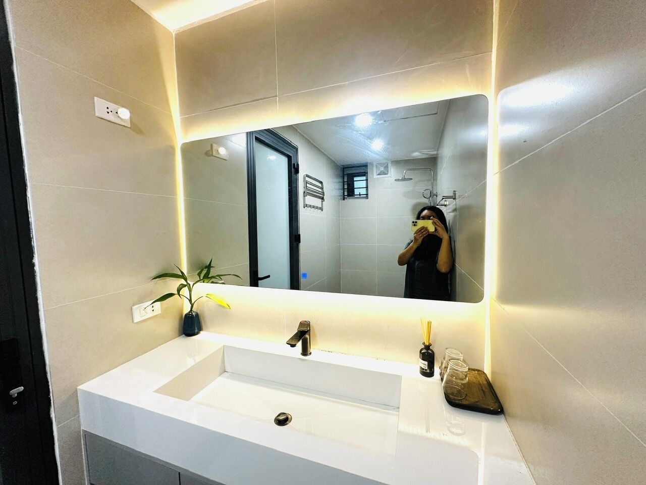 Une salle de bain moderne avec un lavabo blanc, un miroir et une plante en pot.