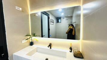 Une salle de bain moderne avec un lavabo blanc, un miroir et une plante en pot.