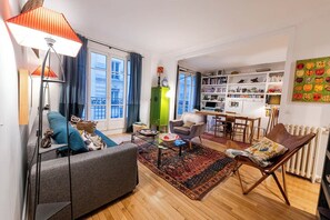 Ein Wohnzimmer mit einer Couch, einem Sessel, einem Couchtisch und einem Bücherregal.
