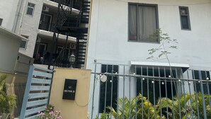 A multi-story building with balconies, air conditioning units, and a gated entrance. - Hotel Elite One (Gurugram)