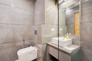 A modern bathroom with a glass partition, a white sink, and a shower area.